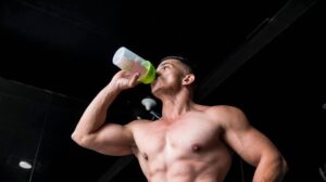 Young shirtless man with abs drinking a protein shake