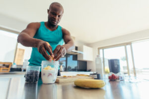 Man,Preparing,Milk,Shake,In,Kitchen.,Athletic,Man,Adding,Fruits