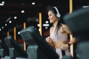 Happy,Beautiful,Young,Asian,Woman,Running,On,Treadmill,And,Listening