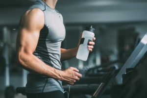 A man running on a treadmill with a water bottle