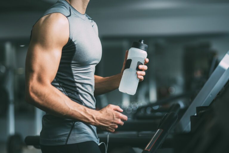 A man running on a treadmill with a water bottle