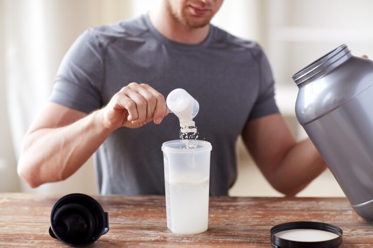 A man scooping protein powder into a bottle.