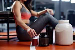 Woman takes pre-workout supplements.